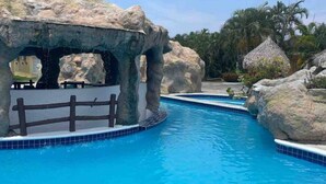 A pool area with a rocky structure and a wooden fence. - Home at the beach!  (Jutiapa)