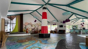 A lobby with a large red and white lighthouse sculpture, a mural of seashells, and a colorful floor design. - Home at the beach!  (Jutiapa)