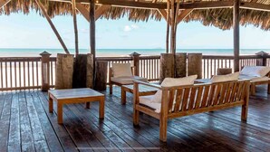 A wooden deck with a thatched roof overlooking a beach. - Home at the beach!  (Jutiapa)