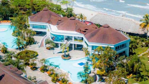 A resort with multiple swimming pools, a beach, and a large building with a thatched roof. - Home at the beach!  (Jutiapa)