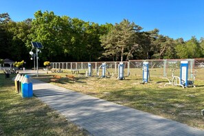 Ein Park mit Fitnessgeräten, Bänken und einem gepflasterten Weg.