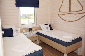 A room with two single beds, a small desk, a lamp, and a window with a view of the outdoors. - Air-conditioned holiday homes, 2 bedrooms (Mielenko)
