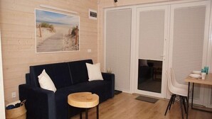 Un'accogliente zona giorno con un divano blu scuro, un tavolino in legno e un quadro a tema spiaggia.