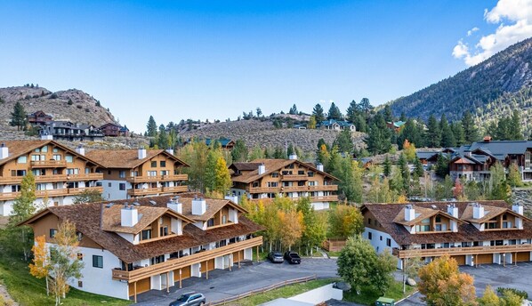 A cluster of chalet-style buildings with multiple balconies, set against a backdrop of mountains and autumn foliage. - Large, renovated Interlaken condo that accommodates 10! (June Lake)