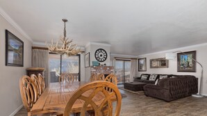 A spacious living room with a wooden dining table and chairs, a brown sofa, and a chandelier. - Large, renovated Interlaken condo that accommodates 10! (June Lake)