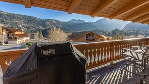 A wooden balcony with a grill, overlooking a mountainous landscape with houses. - Large, renovated Interlaken condo that accommodates 10! (June Lake)