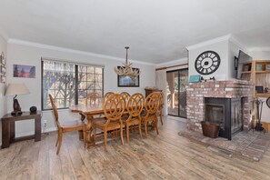A dining area with a wooden table and chairs, a chandelier, a fireplace, and a clock on the wall. - Large, renovated Interlaken condo that accommodates 10! (June Lake)