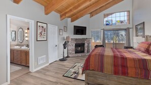 A bedroom with a large bed, a fireplace, and a view of the outdoors. - Large, renovated Interlaken condo that accommodates 10! (June Lake)