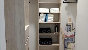 Een inloopkast met houten vloer, planken voor opgevouwen kleding en een kledingroede.