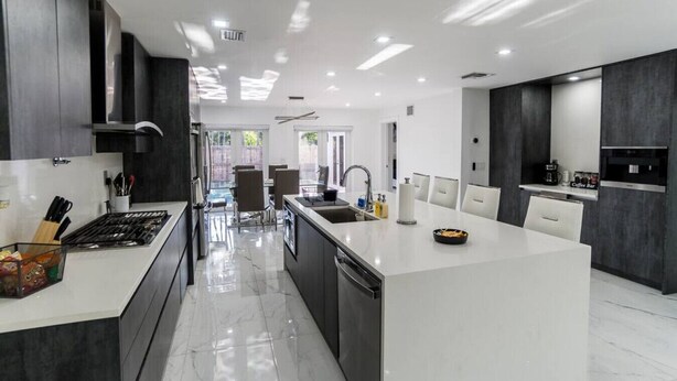 A modern kitchen with a central island, dark cabinetry, and a bright, well-lit space. - Modern Luxury, 2 Mi From Beach! (Fort Lauderdale)