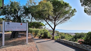 A sign for Saint Roch Hotel - Cap Corse with a view of the sea and trees.
