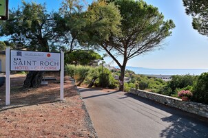 Cartel del Hotel Saint Roch - Cap Corse, con vista al mar y árboles.