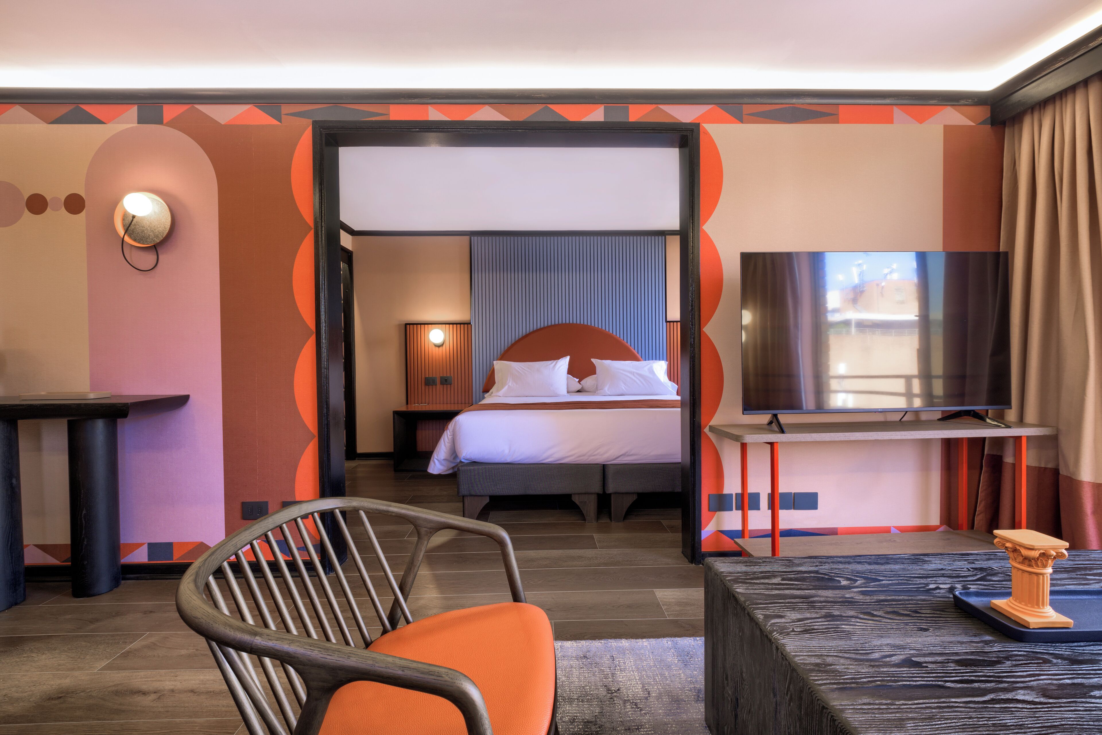 A hotel room with a bed, a TV, a chair, and a table.