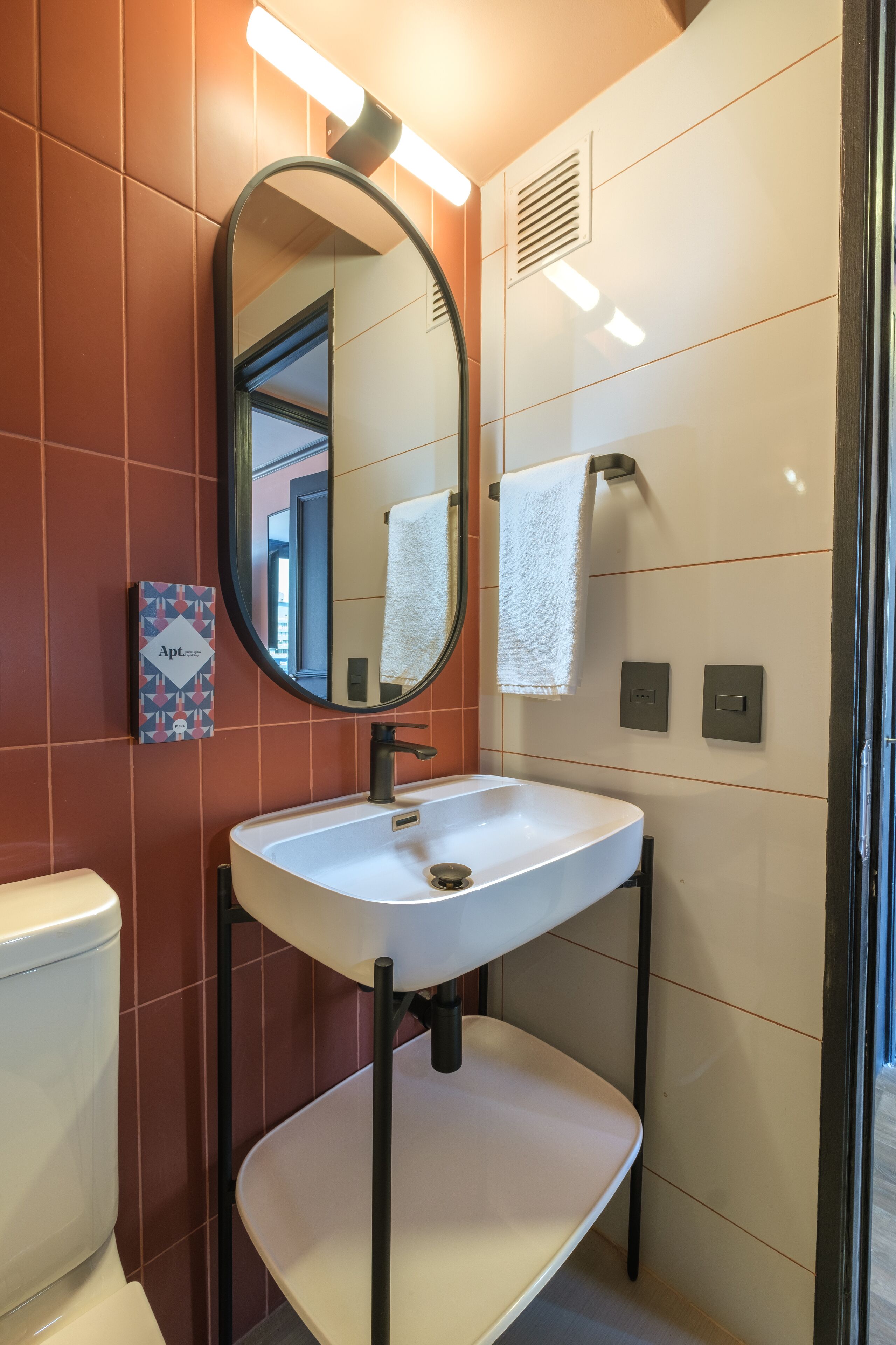 A modern bathroom with a white sink, a mirror, and a towel hanging on a rack.