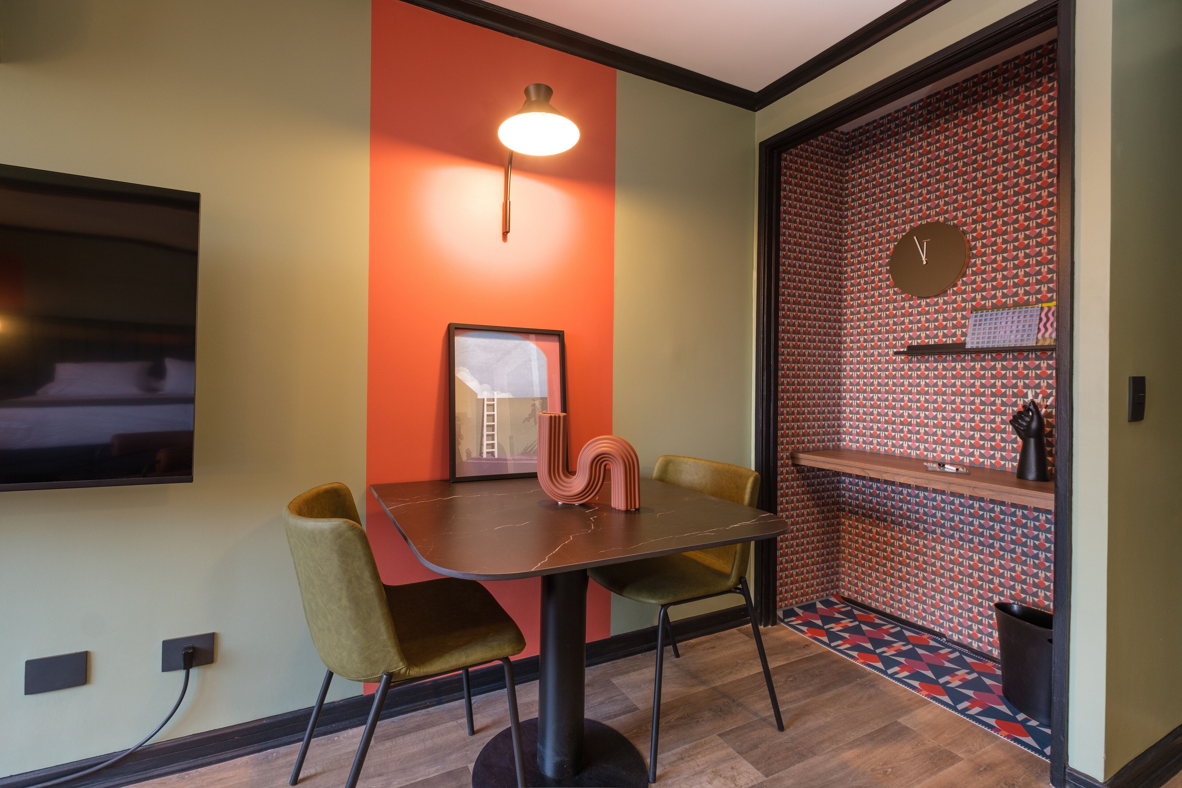 A modern dining area with a table, chairs, a wall-mounted TV, and a clock.