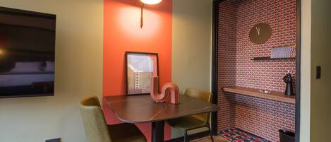 A modern dining area with a table, chairs, a wall-mounted TV, and a clock.