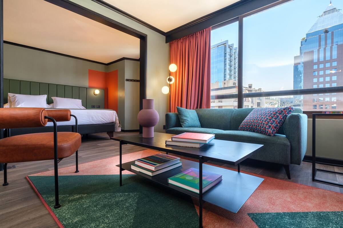 Una habitación de hotel con una cama, un sofá, una mesita de centro y vistas a la ciudad.