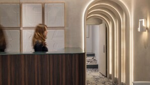 Ein modern gestalteter Empfangsbereich mit einer Rezeption, gerahmten Kunstwerken an der Wand und einem Marmorboden.
