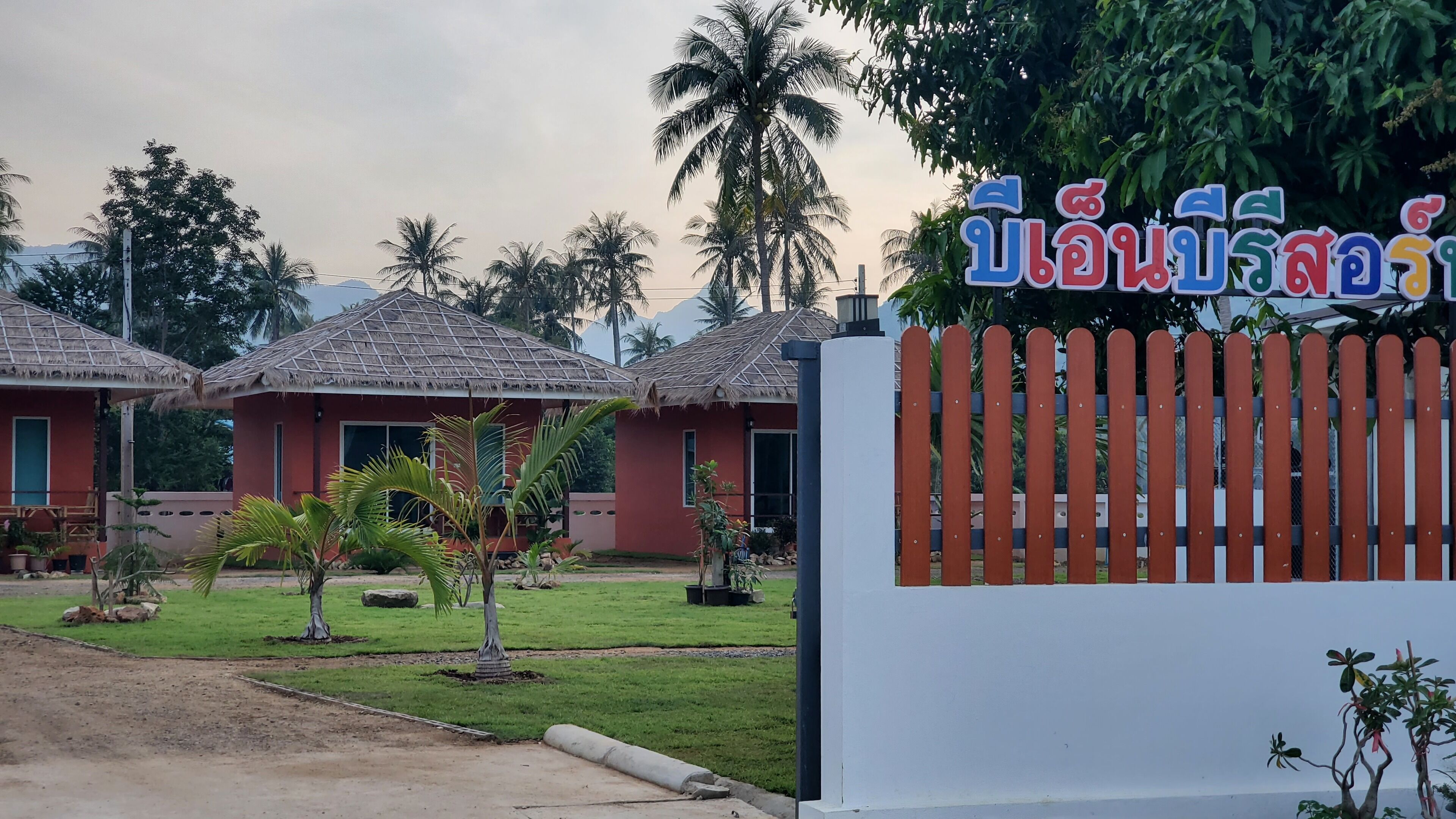 Un hotel de estilo cabaña con techos de paja y entrada con cerramiento.
