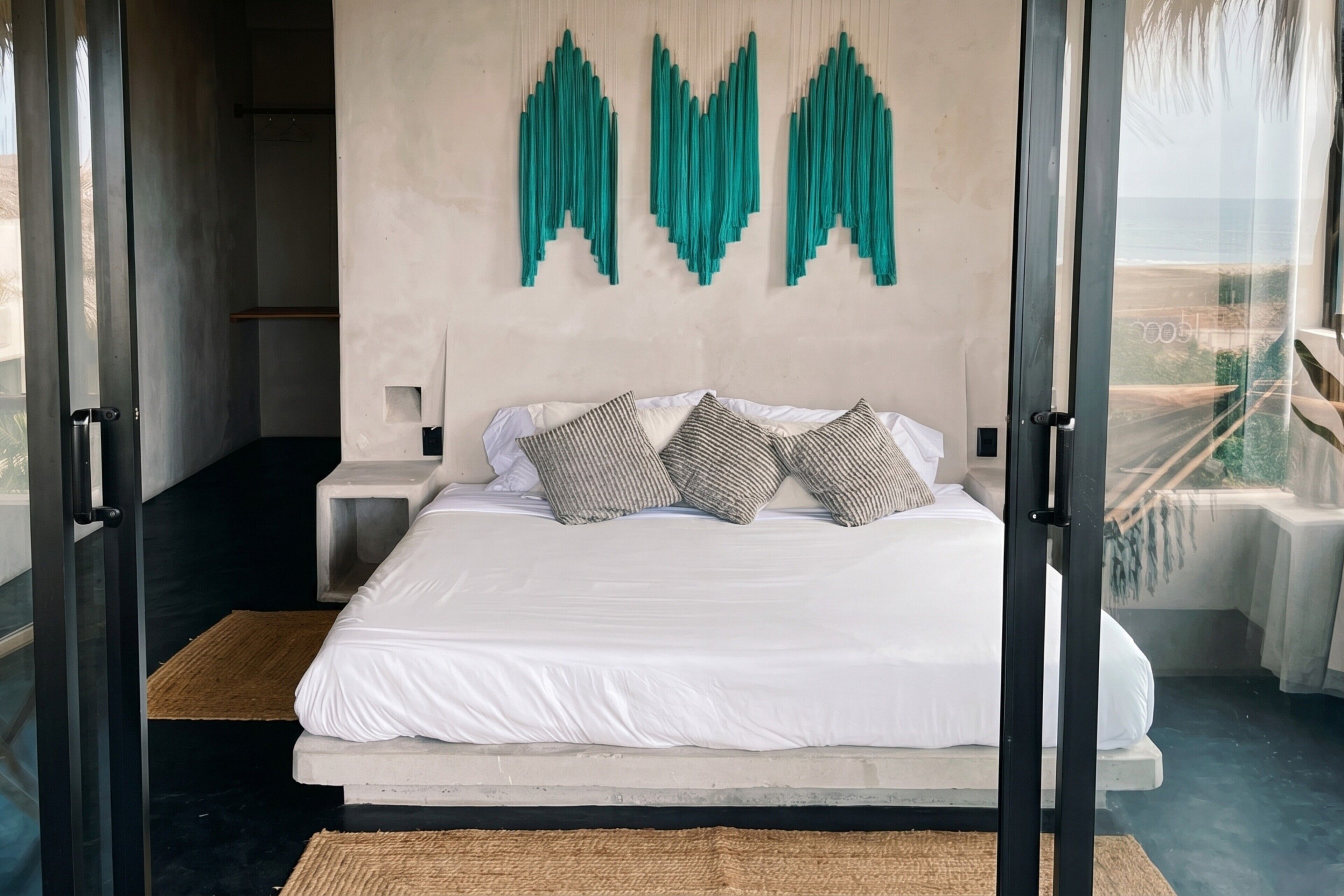 Ein modernes Schlafzimmer mit einem großen Bett, Meerblick und einem außergewöhnlichen Wandkunstwerk.