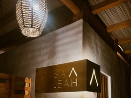 Un letrero de madera con letras iluminadas que dicen “CASA LEAH” en un ambiente rústico.
