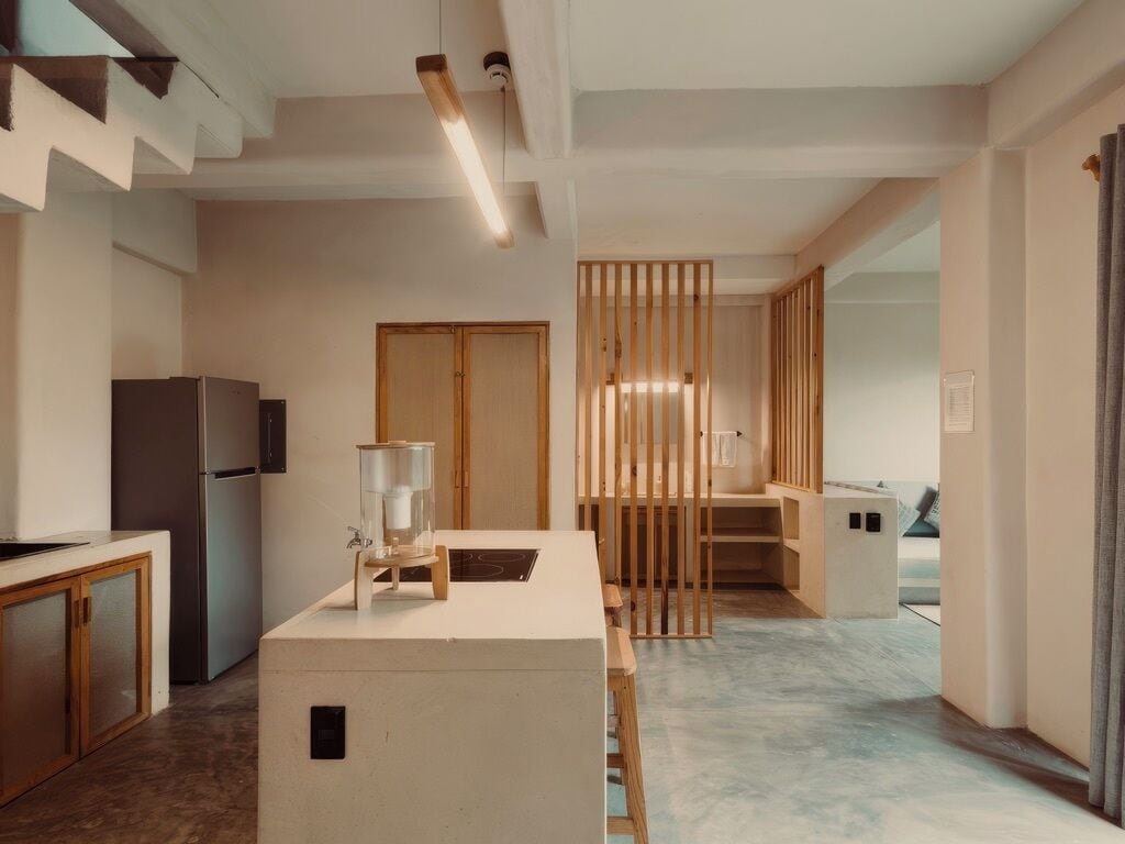 A modern kitchen with a central island, wooden accents, and a built-in refrigerator.