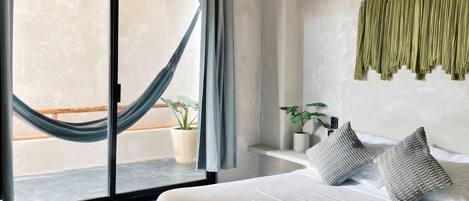 A bedroom with a bed, a window with a view, a curtain, and a wall-mounted plant.