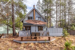 Uma cabana com varanda, área de estar externa e chaminé.