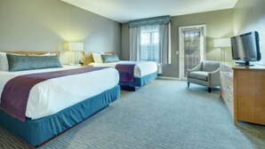 Ein Hotelzimmer mit zwei Betten, einem Fernseher, einem Schreibtisch und einem Stuhl.