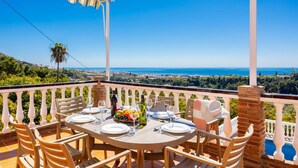 A table set for dining with a view of the sea and landscape.