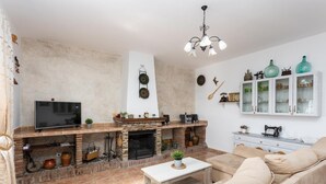 A living room with a fireplace, television, sofa, and decorative items.