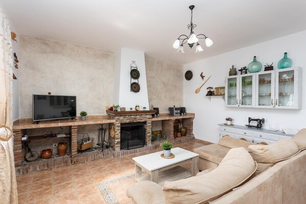 Ein Wohnzimmer mit Kamin, Fernseher, Sofa und Dekorationselementen.