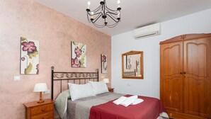 A bedroom with a bed, a nightstand, a dresser, a wardrobe, and floral wall art.