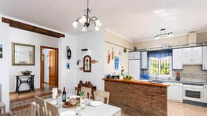 A spacious kitchen with a central island, white cabinets, and a dining area with a table set for four.