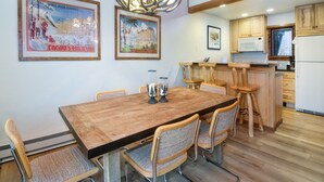 Un coin repas avec une table et des chaises en bois, un lustre et des tableaux encadrés accrochés au mur.