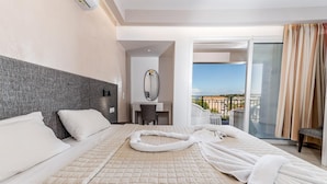 Une chambre d’hôtel avec un grand lit, un bureau, une chaise, un miroir et un balcon avec vue.