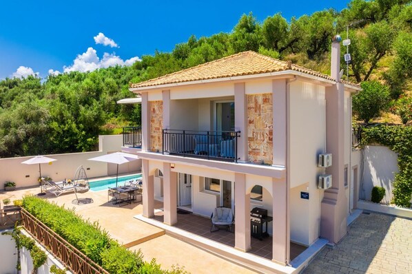 A two-story building with a balcony, a swimming pool, and outdoor seating.