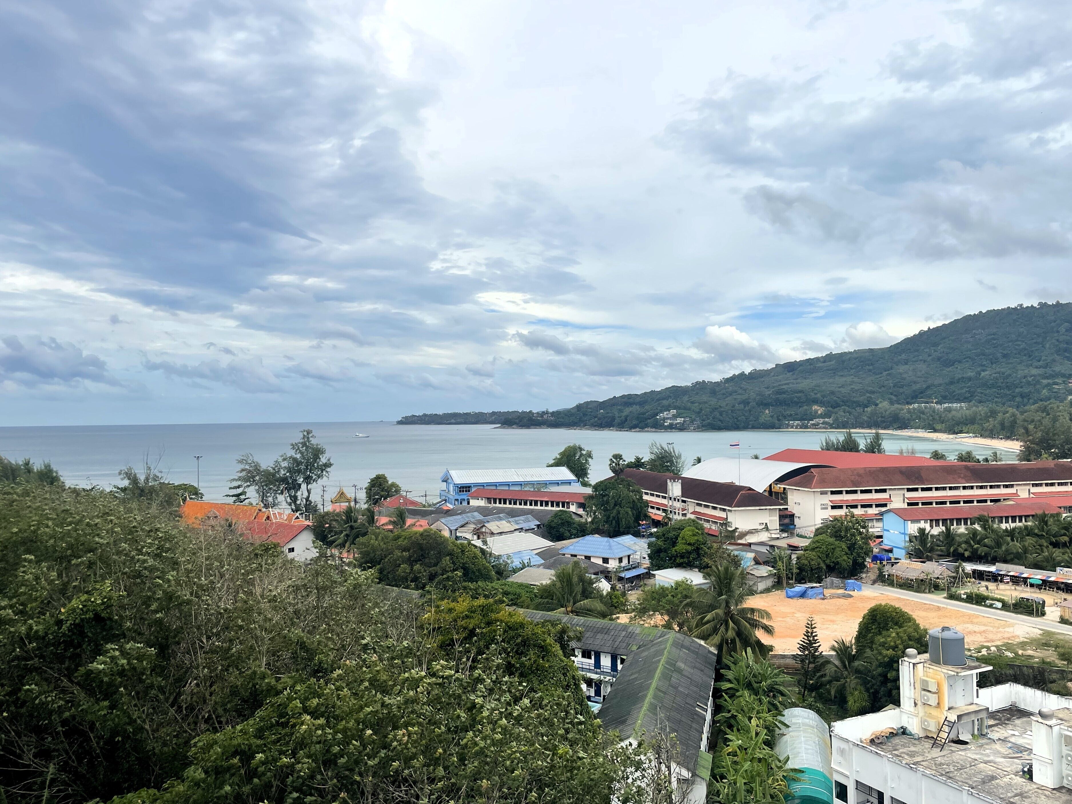 A coastal town with buildings, a beach, and a hilly backdrop.