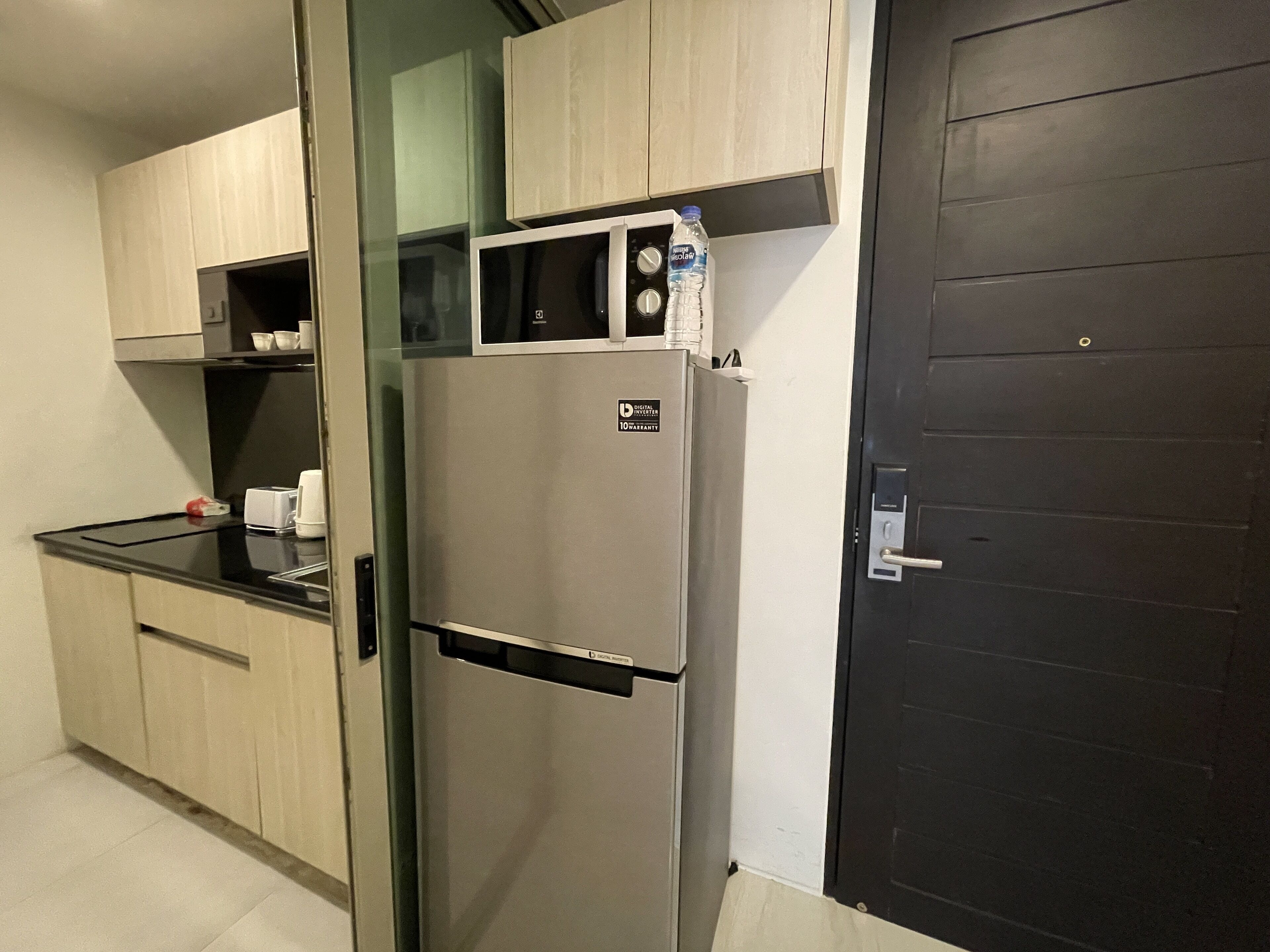 A kitchen with a stainless steel refrigerator, wooden cabinets, and a black countertop.