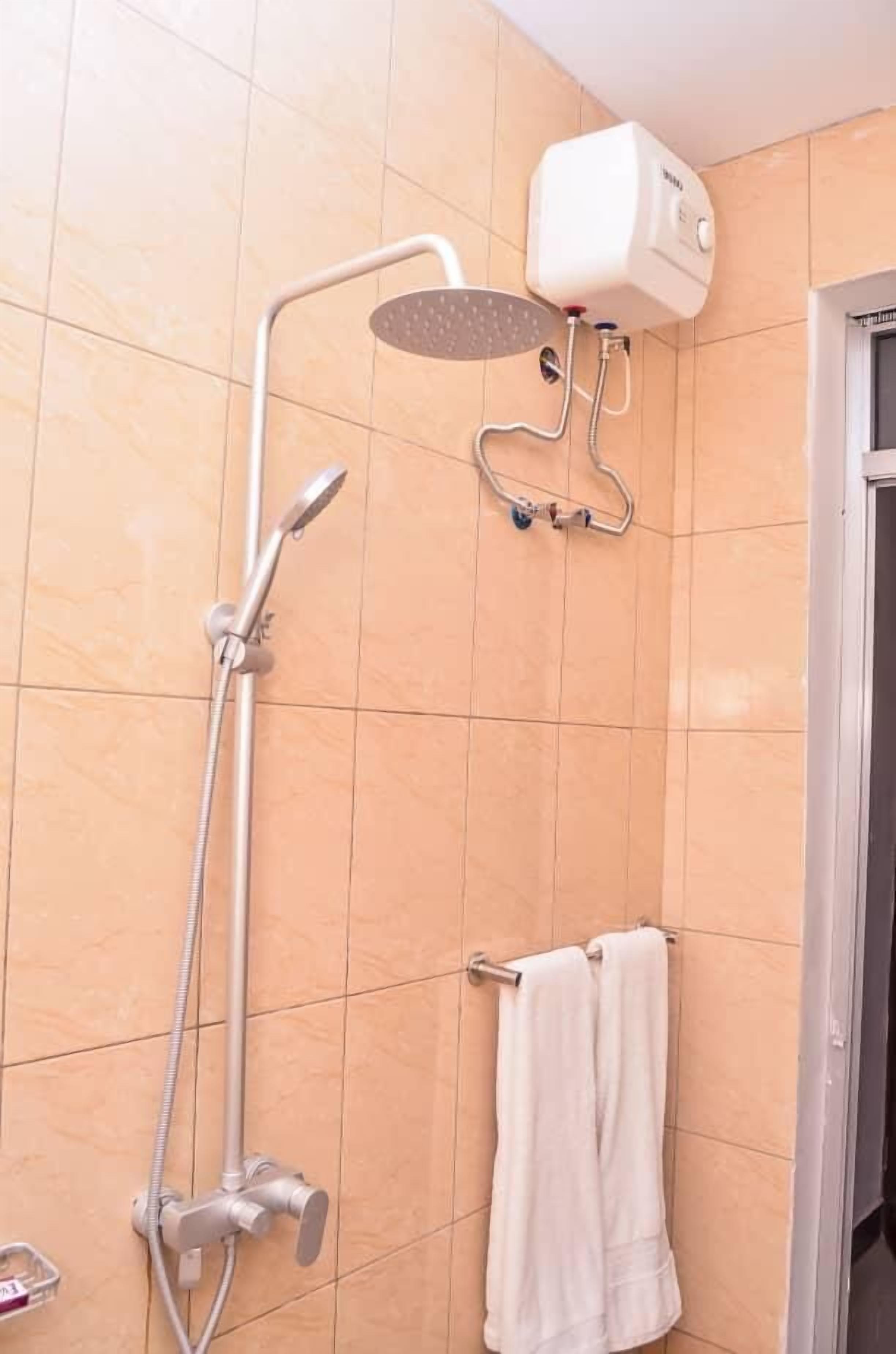 A bathroom with a shower, a towel rack, and a water heater.