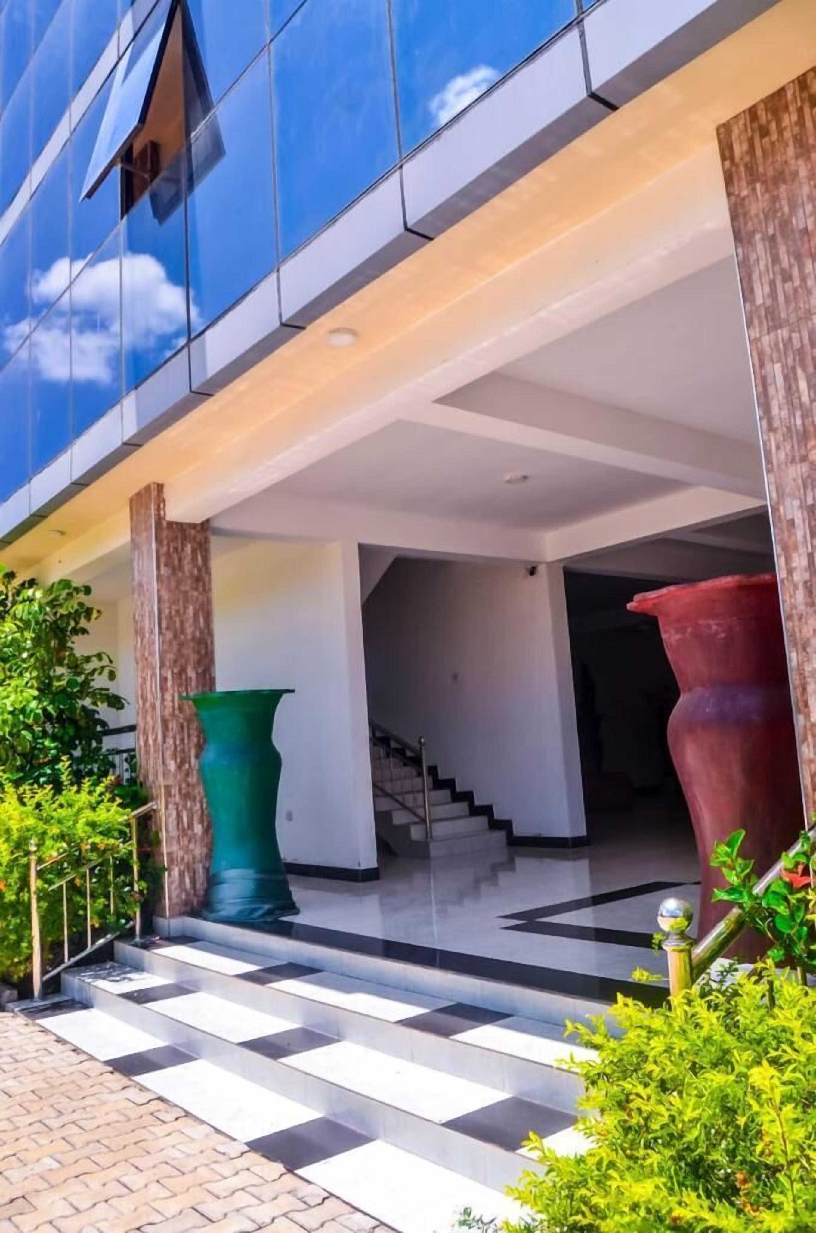 Un edificio moderno con fachada de vidrio, una escalera y grandes jarrones decorativos.