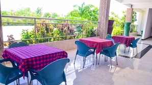 A terrace with tables and chairs, covered with red and blue checkered tablecloths, and a view of greenery. - Muhako Hotel (Dar es Salaam)
