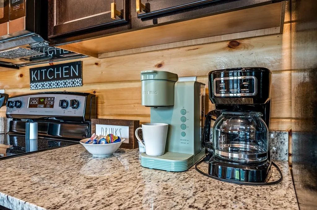 A kitchen with a coffee maker, a kettle, and a coffee machine on the counter.