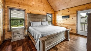 Quarto com painéis de madeira, uma cama, duas mesas de cabeceira e uma janela.