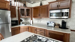 Una cocina moderna con electrodomésticos de acero inoxidable, armarios de madera y una isla central con estufa a gas.