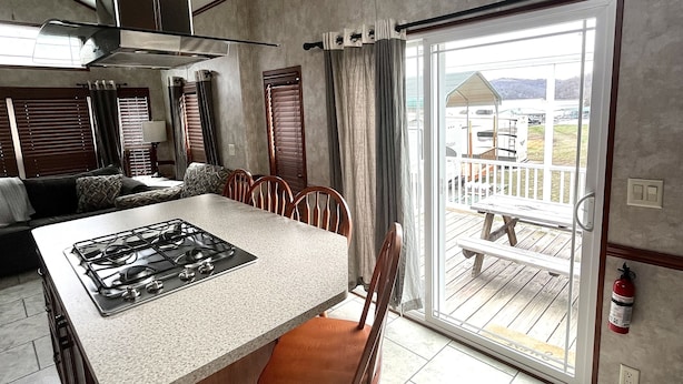 Una cocina moderna con una isla central, un comedor con sillas, un amplio ventanal corredero a una terraza y un ventilador de techo.