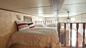 Un dormitorio con cama, cabecero de madera y vista al exterior a través de una ventana.