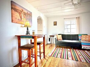 Ein Wohnzimmer mit einem Holzesstisch, einer Couch und einem bunten Teppich.