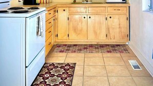 Una cocina con armarios de madera, una estufa blanca, un microondas y un tapete estampado.