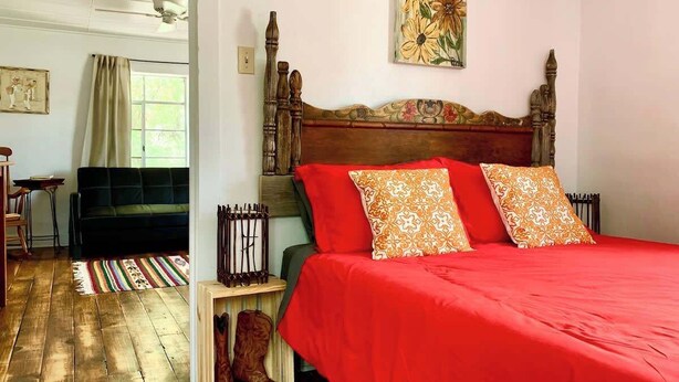 A bedroom with a wooden headboard, a red bedspread, and patterned pillows. - La Casita | Southwest Studio Near Downtown Raton (Raton)